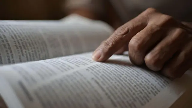 Dedo de pessoa em cima de trecho da Bíblia