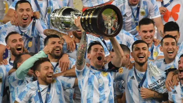 Messi levanta o troféu da Copa América em meio aos seus companheiros, após a vitória da Argentina no torneio de 2021