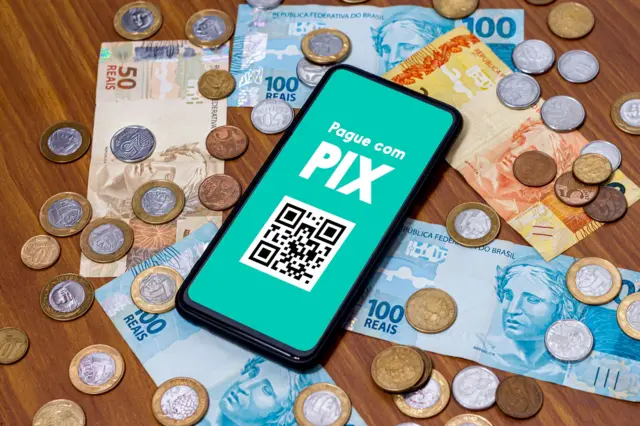 Celular com pix e mesa cheia de reais